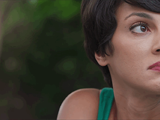 Close-up shot from the movie “An Unquiet Mind” of a woman with short dark hair and a green top, looking pensively to her right.